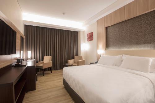 a hotel room with a bed and a table and chairs at BEST WORLD KINDAI HOTEL in Banjarmasin
