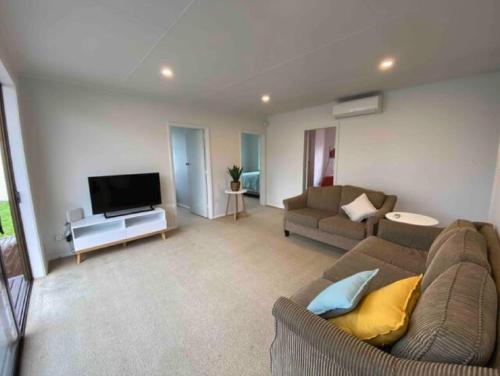 a living room with a couch and a flat screen tv at Our Basic Bach - Mangakino in Mangakino