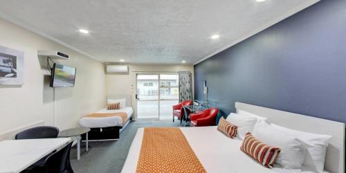 Habitación de hotel con 2 camas y escritorio en Capri on Fenton en Rotorua