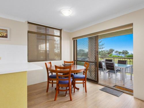 a dining room with a table and chairs and a balcony at Tradewinds 1 on Kingscliff Beach in Kingscliff