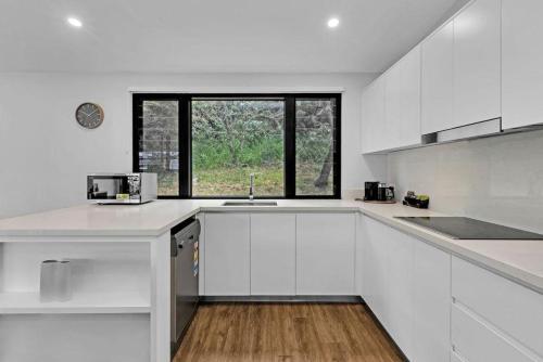 a white kitchen with a sink and a window at Reflections Seal Rocks - Holiday Park in Smiths Lake