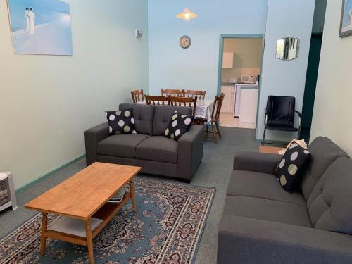 Una sala de estar con dos sofás y una mesa. en Upstairs Beachfront Unit in Central Location, en Victor Harbor