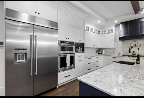 a kitchen with a stainless steel refrigerator and white cabinets at Big and Luxury House in Surrey