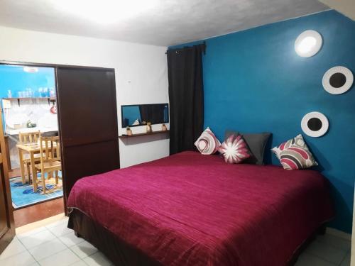 een slaapkamer met een paars bed met een blauwe muur bij PANCHITO’S in Isla Mujeres