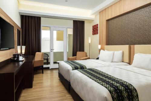 a hotel room with two beds and a desk at BEST WORLD KINDAI HOTEL in Banjarmasin