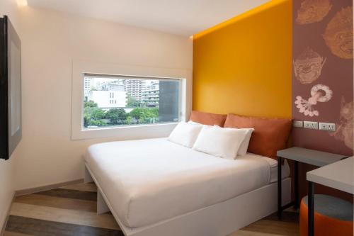 a bedroom with a white bed with a yellow wall at Jono Bangkok Asok Hotel in Bangkok