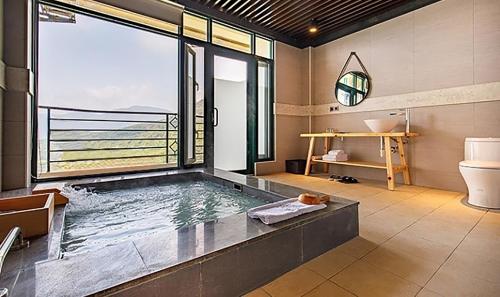 a bathroom with a tub with a view of the ocean at Yanmin Hot Spring Resort in Taipei