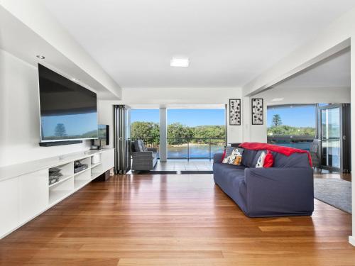 a living room with a couch and a flat screen tv at Sunset Waters Creekfront Apartment in Kingscliff