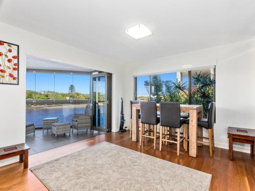 a living room with a table and chairs and a view of the water at Sunset Waters Creekfront Apartment in Kingscliff