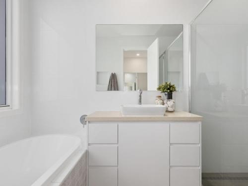 a white bathroom with a sink and a mirror at Sunrise Mansion with Pool in Kingscliff