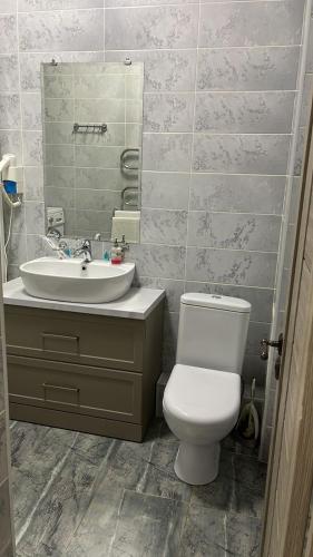 a bathroom with a white toilet and a sink at Апартаменты в центре города ЖК Арман in Aktobe