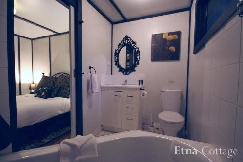 a bathroom with a tub and a toilet and a bed at Tudor Cottages in Mount Dandenong