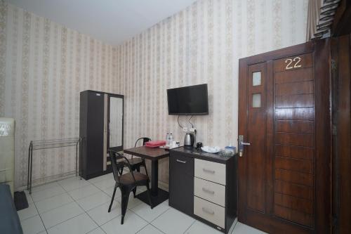 a room with a desk and a table with a television at Hotel Soreang in Bandung