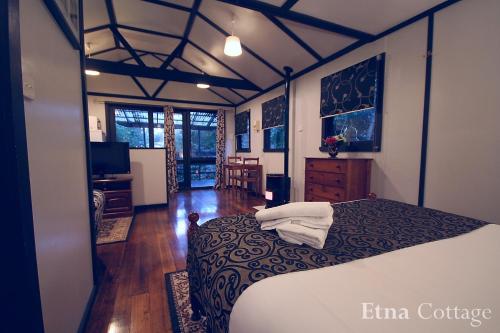 1 dormitorio con 1 cama y TV en Tudor Cottages en Mount Dandenong