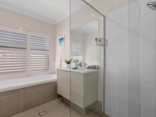a white bathroom with a shower and a sink at Salty Pause at Bondi House - Pet Friendly! in Kingscliff