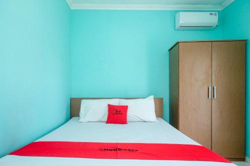 a bedroom with a bed with a red pillow on it at RedDoorz @ Jakal Atas KM 7 in Kejayan