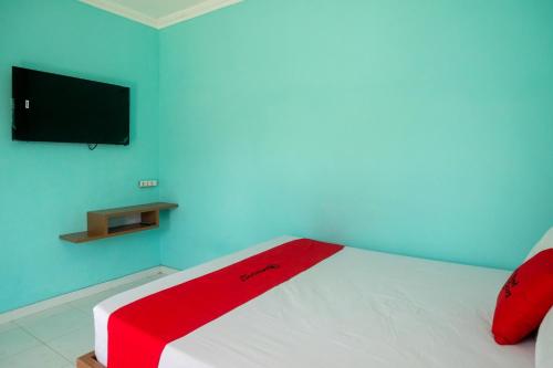 a bedroom with a bed with a red blanket on it at RedDoorz @ Jakal Atas KM 7 in Kejayan