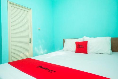 a bed with a red pillow on top of it at RedDoorz @ Jakal Atas KM 7 in Kejayan