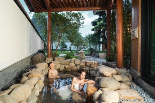 two people in a pool of water with rocks at Yoko Onsen Quang Hanh in Cẩm Phả