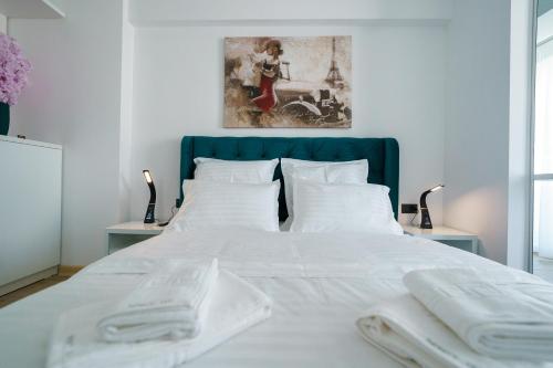 a white bed with white sheets and a blue headboard at The Queen Infinity Beach Pool&Spa Mamaia Nord in Mamaia Nord