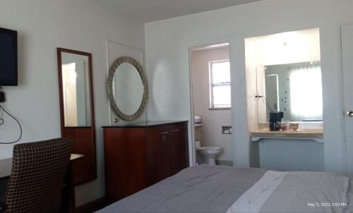1 dormitorio con cama, espejo y lavamanos en Travelers Beach Inn, en Ventura