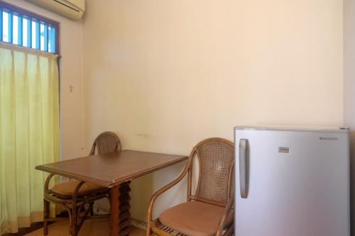 a kitchen with a table and a white refrigerator at My Cafe Hotel near UGM Yogyakarta Mitra RedDoorz in Kejayan