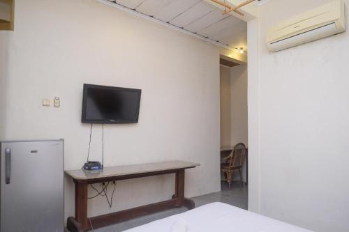 a room with a table and a tv on the wall at My Cafe Hotel near UGM Yogyakarta Mitra RedDoorz in Kejayan