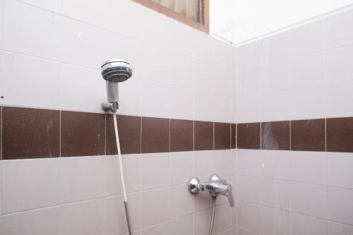 a shower with a hose attached to a wall at My Cafe Hotel near UGM Yogyakarta Mitra RedDoorz in Kejayan
