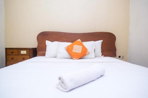 an orange pillow sits on a bed with white pillows at My Cafe Hotel near UGM Yogyakarta Mitra RedDoorz in Kejayan