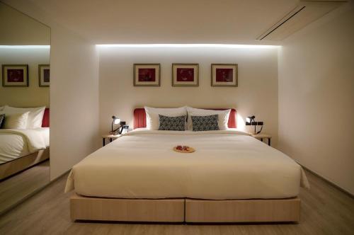 a bedroom with a large white bed with a mirror at Hotel Midtown Ratsada in Phuket Town