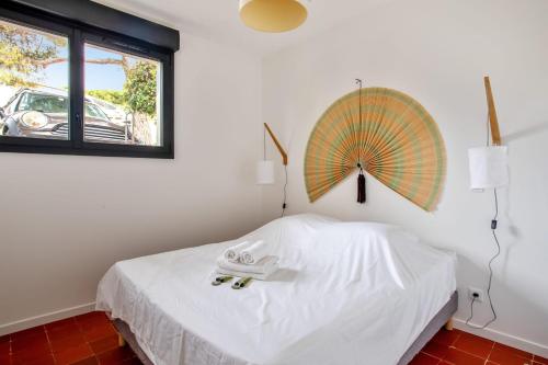 um quarto com uma cama branca e um guarda-chuva na parede em Villa Canoem - Welkeys em Cassis