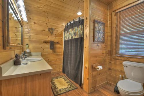 un bagno con servizi igienici e lavandino in una baita di tronchi di Papa Bear Lodge a Blue Ridge