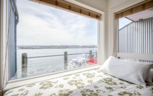 a bedroom with a large window looking out at the water at Coastal Garden - Anchor Pier Lodge in Newport