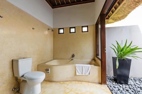 a bathroom with a toilet and a bath tub at Villa Sasoon, 100 mt to Beach in Candidasa