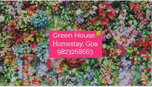 a pink sign in front of a display of flowers at Green House Stay in Mandrem