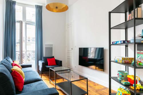 un salon avec un canapé bleu et une télévision dans l'établissement Madeleine's Top Rated 8 Traveller City Center Bordeaux Appartments, à Bordeaux