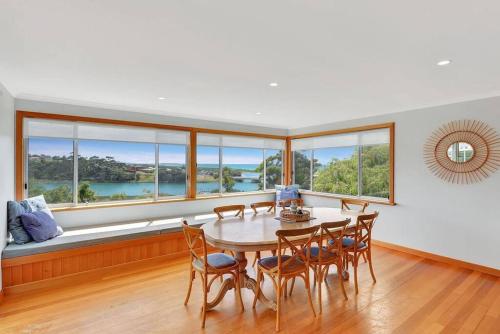 a dining room with a table and chairs and windows at The BEST Scamander Beach House! in Scamander