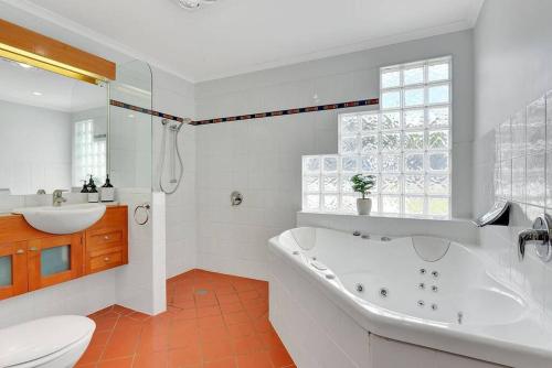 a bathroom with a tub and a sink and a toilet at The BEST Scamander Beach House! in Scamander