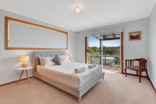 a bedroom with a bed and a large window at The BEST Scamander Beach House! in Scamander