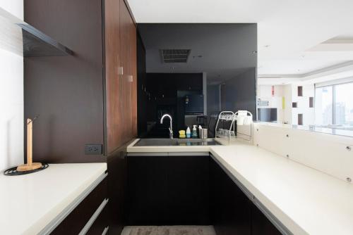 M Estate 2BR Private Residence, 300m to BTS Chit Lom في بانكوك: مطبخ اسود وبيض مع مغسلة وكاونتر