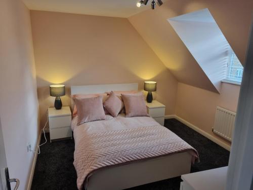 a bedroom with a bed with pink pillows and two lamps at Swindon 6 deluxe doubles 2 with en suite in large house in Swindon
