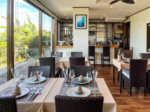 a dining room with tables and chairs and windows at KAYA RESORT KOURIJIMA - Vacation STAY 95302v in Kouri