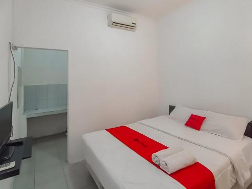 a white bed with red and white pillows in a room at RedDoorz Syariah near RSUD Karawang 2 in Karawang