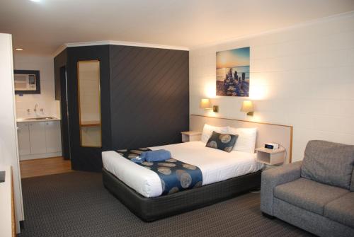 a bedroom with a bed and a couch and a chair at Cunningham Shore Motel in Lakes Entrance