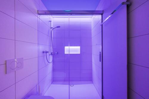 La salle de bains est pourvue d'une douche avec un éclairage violet. dans l'établissement The R Apartment Uetliberg, Klima, Parken - Wallbox, à Geroldswil