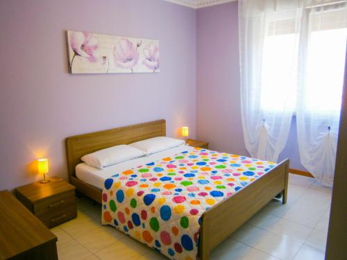 1 dormitorio con 1 cama con un edredón colorido en Appartamento Tintoretto - Agenzia Cocal, en Caorle