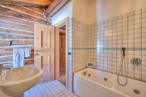 La salle de bains est pourvue d'une baignoire et d'un lavabo. dans l'établissement Chalet Lidia Ski in-Ski out 50m - Happy Rentals, à Livigno