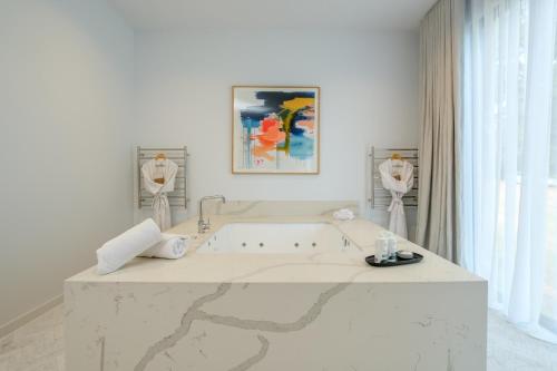 ein weißes Bad mit einer Badewanne und einem Wandgemälde in der Unterkunft Hepburn Springs Escape in Hepburn Springs