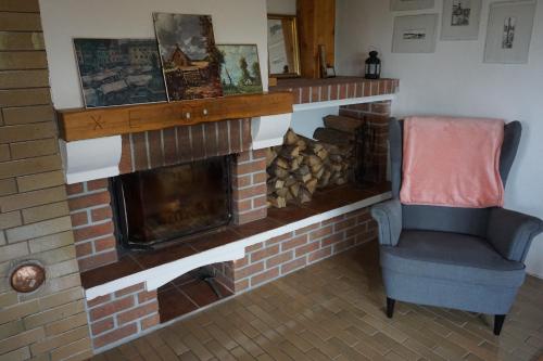 a living room with a brick fireplace and a chair at Chata Žár in Žár