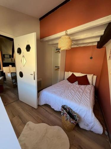 une chambre avec un lit blanc avec un mur orange dans l'établissement Le Montauban - Chic et Cosy en Hypercentre, à Montauban